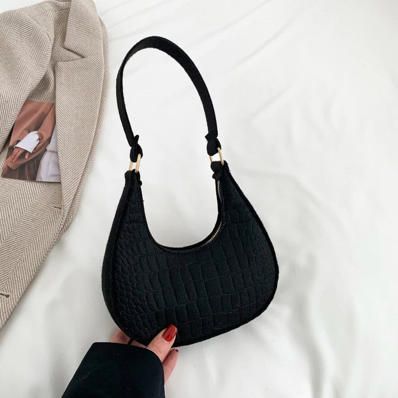 Sac tendance en feutre de haute qualité, au style rétro et élégant. Conçu pour être porté sous le bras ou à l’épaule, il allie simplicité et design moderne.