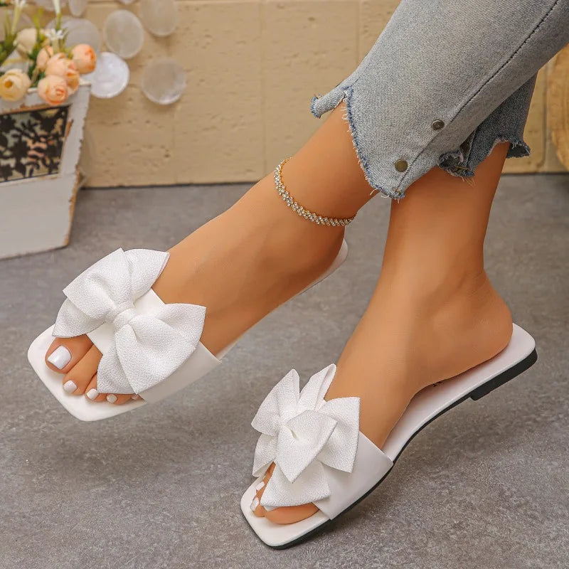 Nouvelles mules plates pour femme 2026, sandales tendance à couleur unie avec nœud décoratif, légères et confortables pour l’extérieur, la plage et un usage quotidien. Disponibles en grandes tailles.