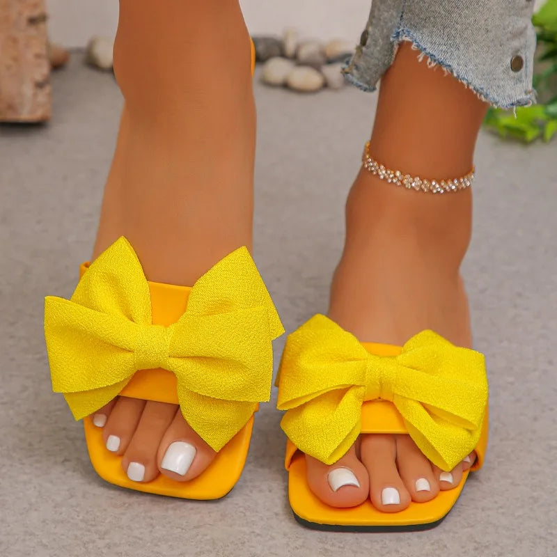 Nouvelles mules plates pour femme 2026, sandales tendance à couleur unie avec nœud décoratif, légères et confortables pour l’extérieur, la plage et un usage quotidien. Disponibles en grandes tailles.