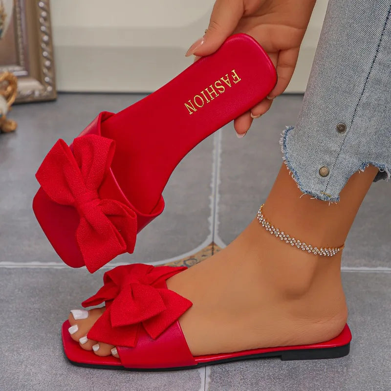 Nouvelles mules plates pour femme 2026, sandales tendance à couleur unie avec nœud décoratif, légères et confortables pour l’extérieur, la plage et un usage quotidien. Disponibles en grandes tailles.