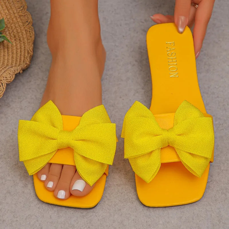 Nouvelles mules plates pour femme 2026, sandales tendance à couleur unie avec nœud décoratif, légères et confortables pour l’extérieur, la plage et un usage quotidien. Disponibles en grandes tailles.