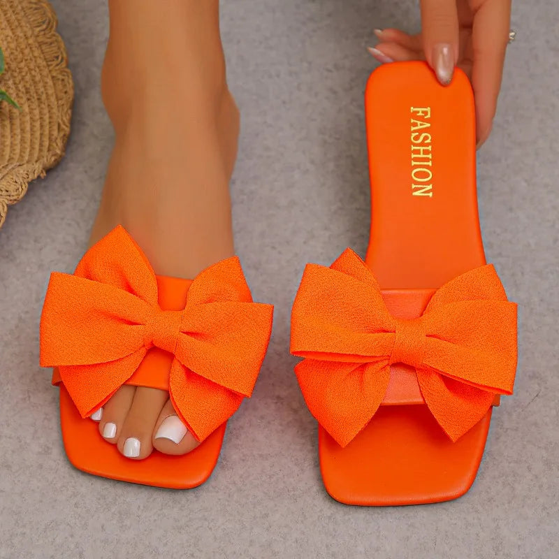 Nouvelles mules plates pour femme 2026, sandales tendance à couleur unie avec nœud décoratif, légères et confortables pour l’extérieur, la plage et un usage quotidien. Disponibles en grandes tailles.