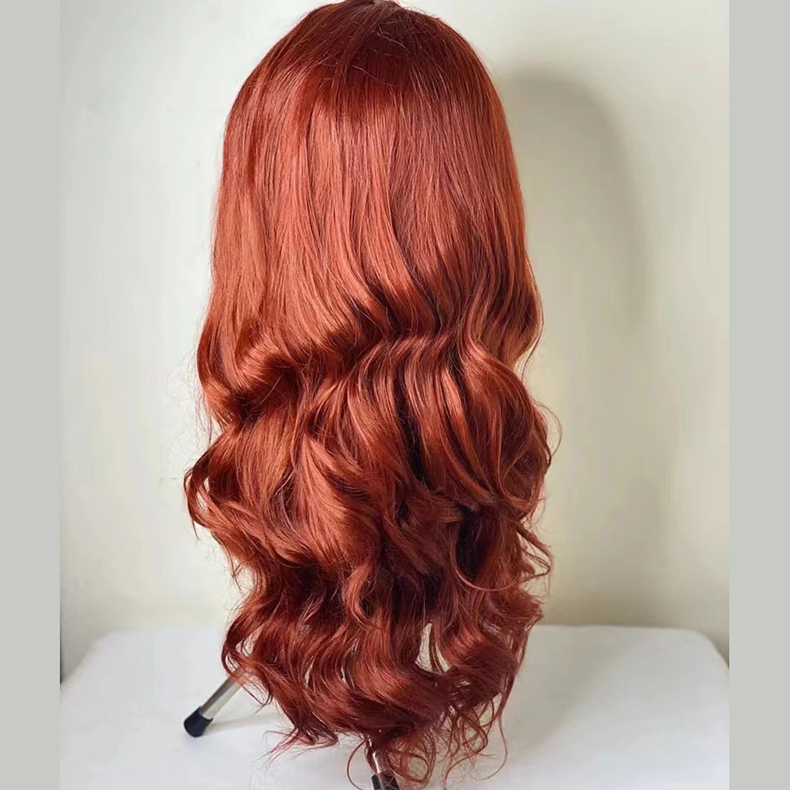 Perruque synthétique à ondulations souples (Body Wave) avec lace frontale, sans colle (glueless). Coloration brun roux cuivré (Auburn/Copper Red) pour un effet naturel et lumineux.