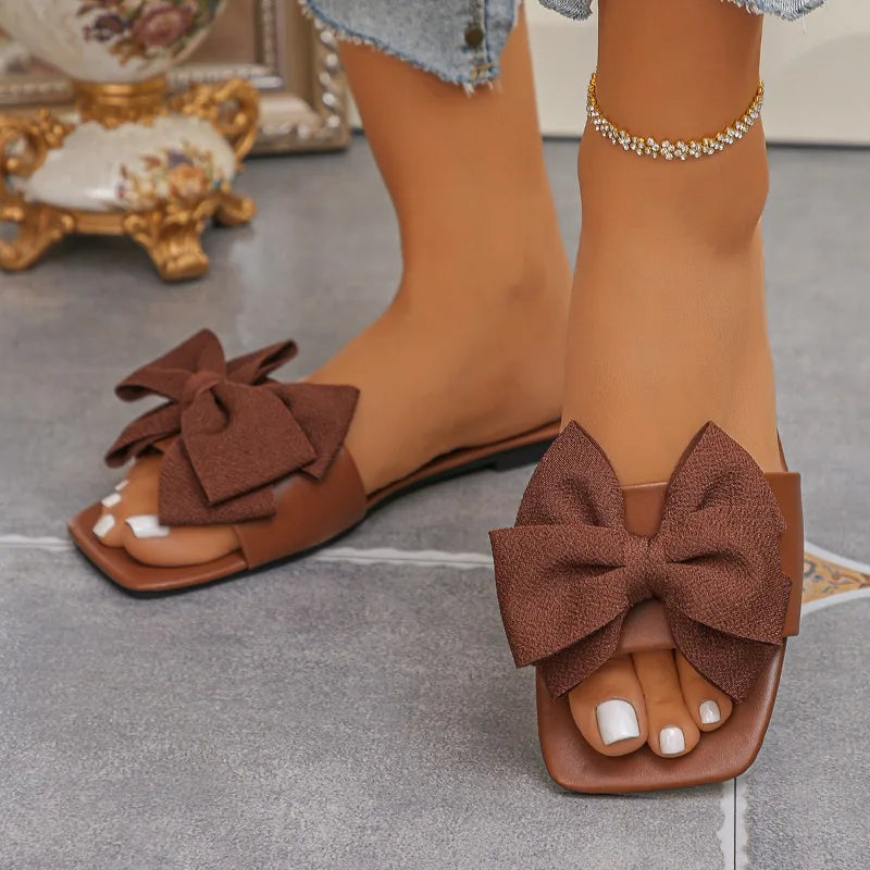 Nouvelles mules plates pour femme 2026, sandales tendance à couleur unie avec nœud décoratif, légères et confortables pour l’extérieur, la plage et un usage quotidien. Disponibles en grandes tailles.