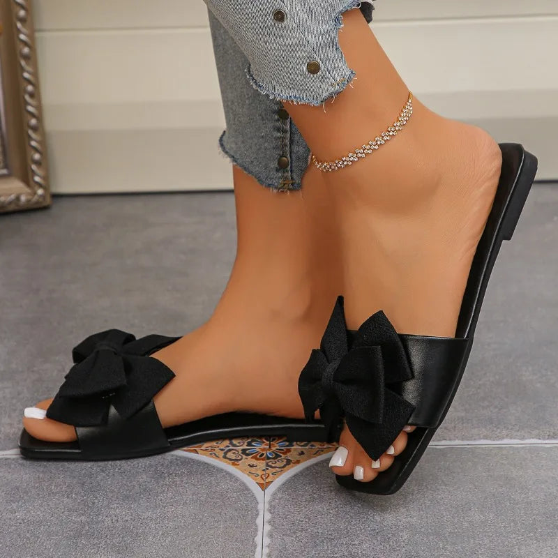 Nouvelles mules plates pour femme 2026, sandales tendance à couleur unie avec nœud décoratif, légères et confortables pour l’extérieur, la plage et un usage quotidien. Disponibles en grandes tailles.