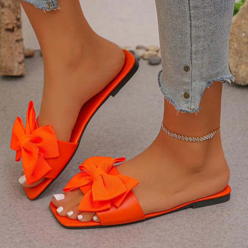 Nouvelles mules plates pour femme 2026, sandales tendance à couleur unie avec nœud décoratif, légères et confortables pour l’extérieur, la plage et un usage quotidien. Disponibles en grandes tailles.