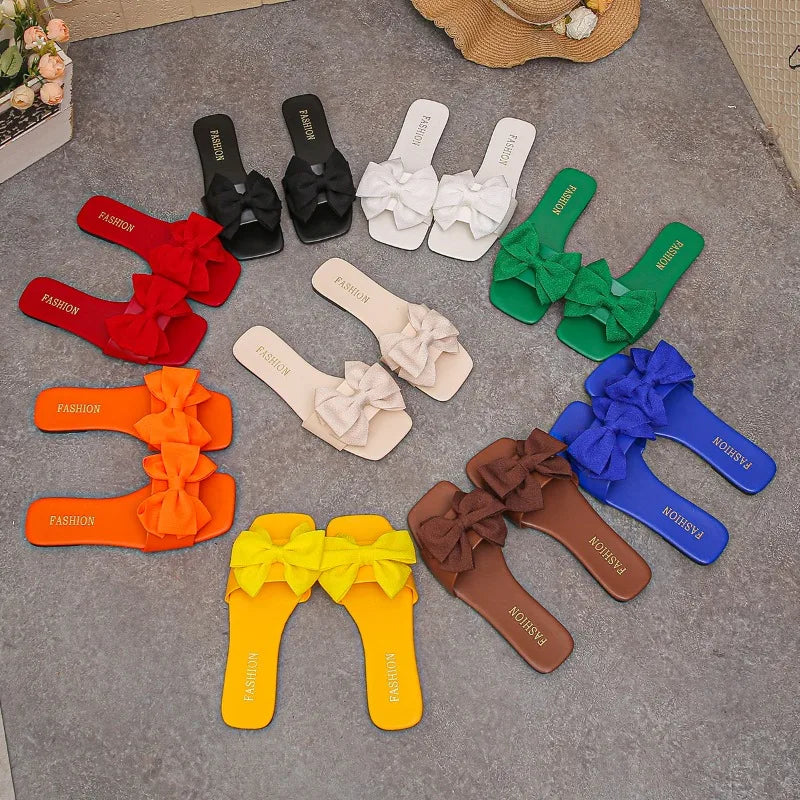 Nouvelles mules plates pour femme 2026, sandales tendance à couleur unie avec nœud décoratif, légères et confortables pour l’extérieur, la plage et un usage quotidien. Disponibles en grandes tailles.