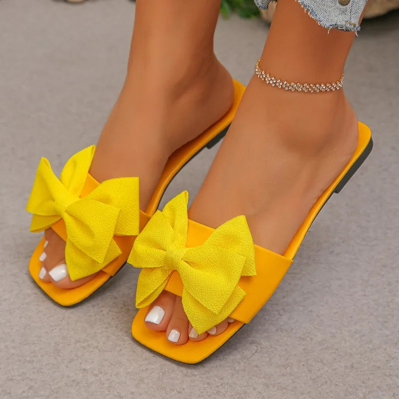 Nouvelles mules plates pour femme 2026, sandales tendance à couleur unie avec nœud décoratif, légères et confortables pour l’extérieur, la plage et un usage quotidien. Disponibles en grandes tailles.