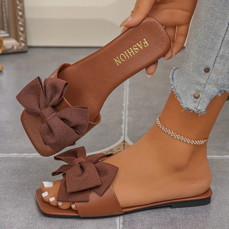 Nouvelles mules plates pour femme 2026, sandales tendance à couleur unie avec nœud décoratif, légères et confortables pour l’extérieur, la plage et un usage quotidien. Disponibles en grandes tailles.