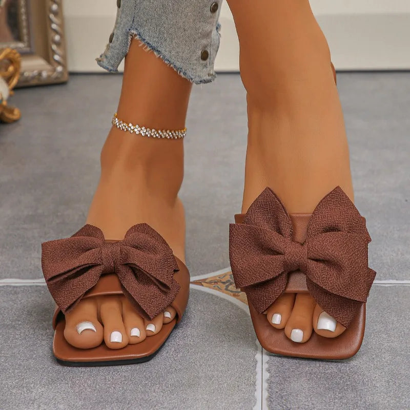 Nouvelles mules plates pour femme 2026, sandales tendance à couleur unie avec nœud décoratif, légères et confortables pour l’extérieur, la plage et un usage quotidien. Disponibles en grandes tailles.