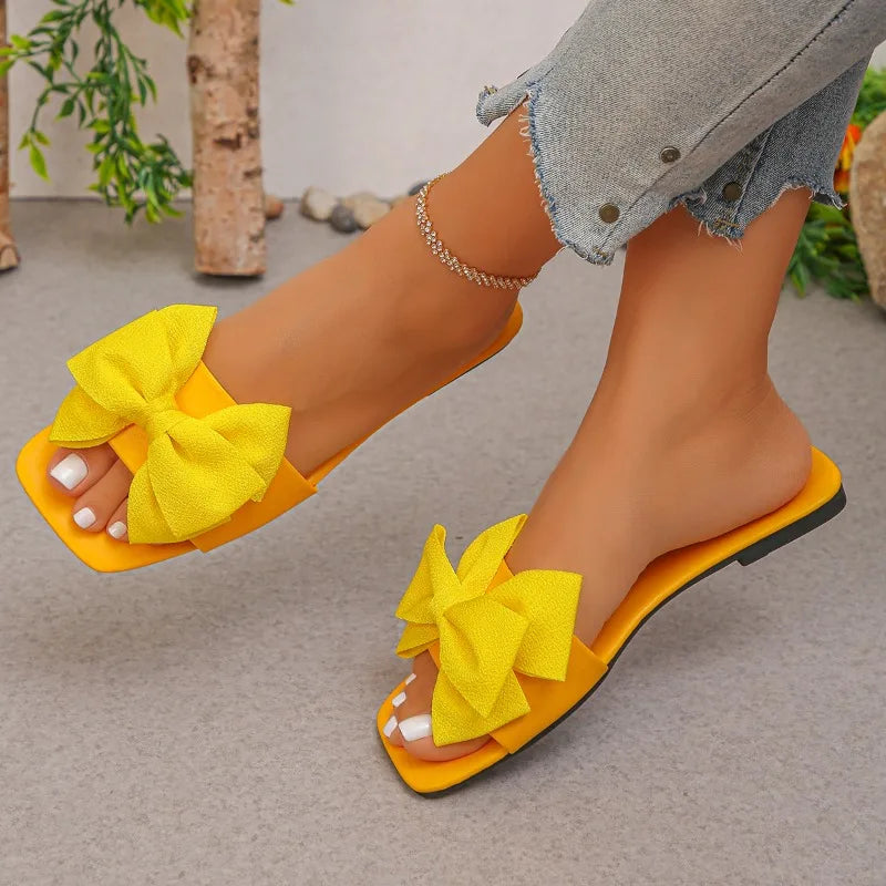 Nouvelles mules plates pour femme 2026, sandales tendance à couleur unie avec nœud décoratif, légères et confortables pour l’extérieur, la plage et un usage quotidien. Disponibles en grandes tailles.