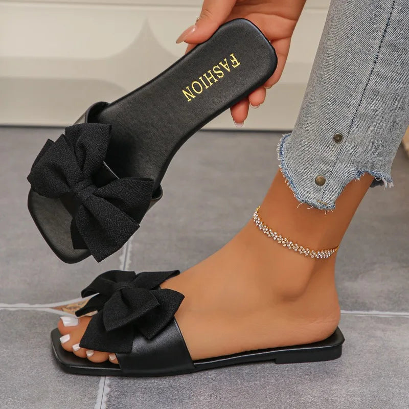 Nouvelles mules plates pour femme 2026, sandales tendance à couleur unie avec nœud décoratif, légères et confortables pour l’extérieur, la plage et un usage quotidien. Disponibles en grandes tailles.