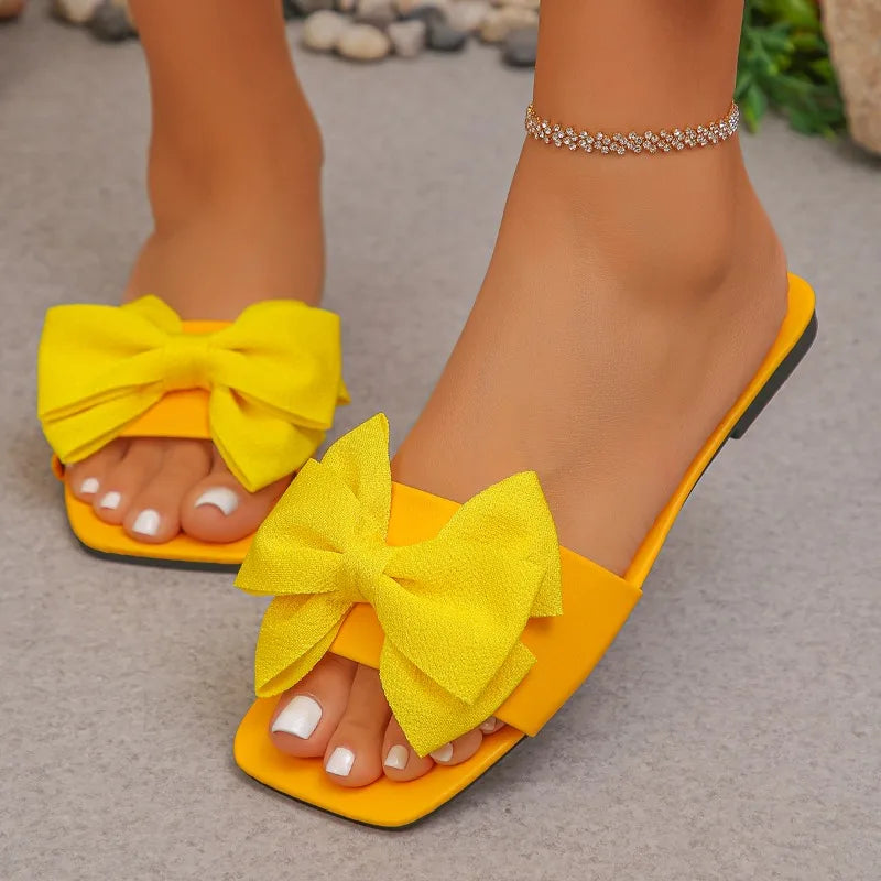 Nouvelles mules plates pour femme 2026, sandales tendance à couleur unie avec nœud décoratif, légères et confortables pour l’extérieur, la plage et un usage quotidien. Disponibles en grandes tailles.