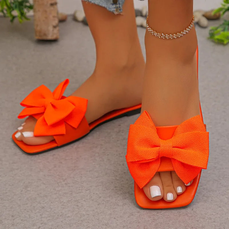 Nouvelles mules plates pour femme 2026, sandales tendance à couleur unie avec nœud décoratif, légères et confortables pour l’extérieur, la plage et un usage quotidien. Disponibles en grandes tailles.