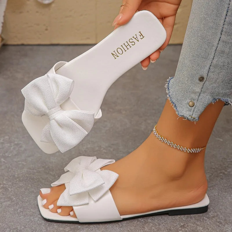 Nouvelles mules plates pour femme 2026, sandales tendance à couleur unie avec nœud décoratif, légères et confortables pour l’extérieur, la plage et un usage quotidien. Disponibles en grandes tailles.
